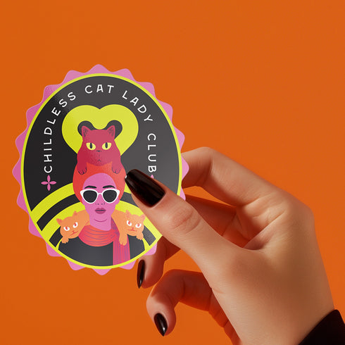 Vibrant oval sticker reading "Childless Cat Lady Club". Features cartoon woman with sunglasses surrounded by cats. Bold retro design in pink, yellow, and red.